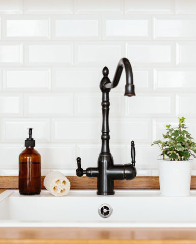 Kitchen with white sink and black faucet wooden countertop. Stylish trendy white ceramic brick wall pattern as background. Eco friendly kitchen concept